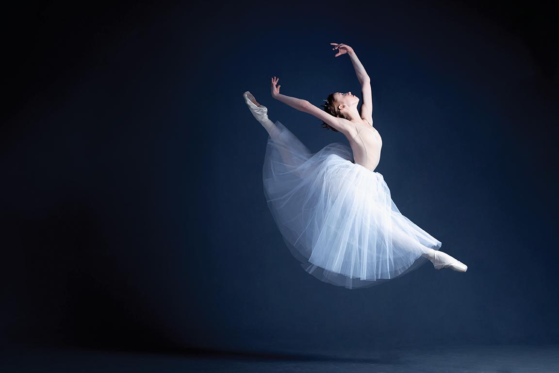 Young ballerina is dancing in a dark photostudio
